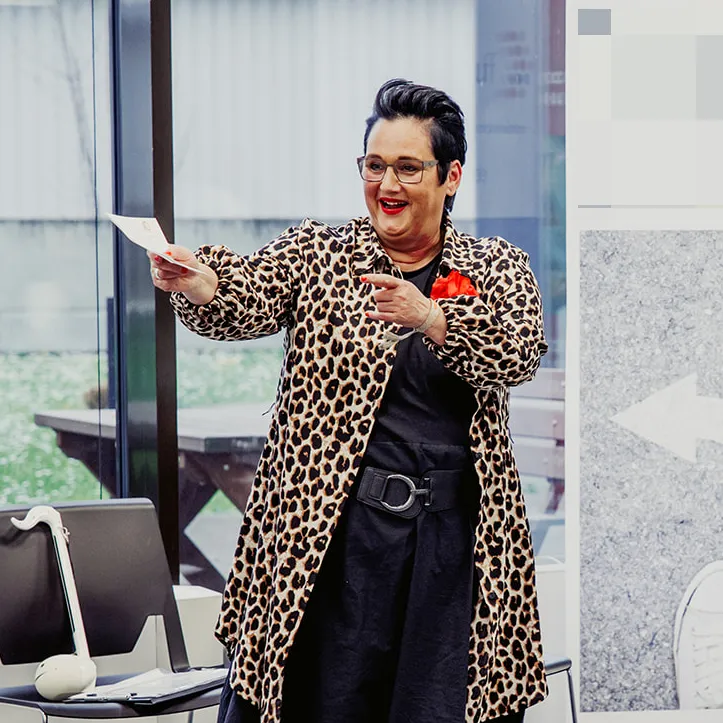 Frau hält lächelnd einen Zettel hoch.