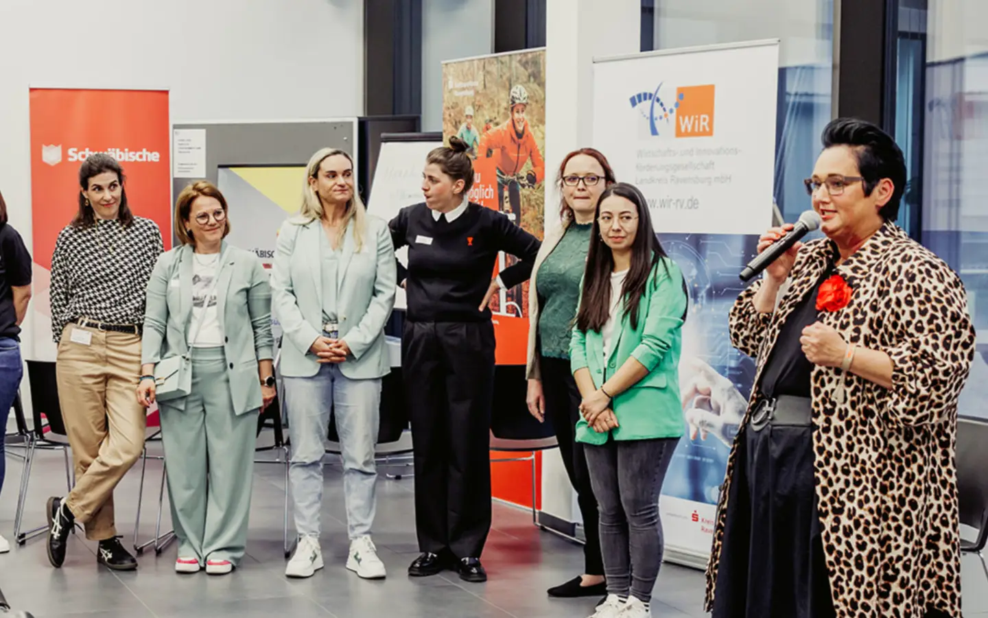 Frau spricht zu einer Gruppe von Menschen im Raum.