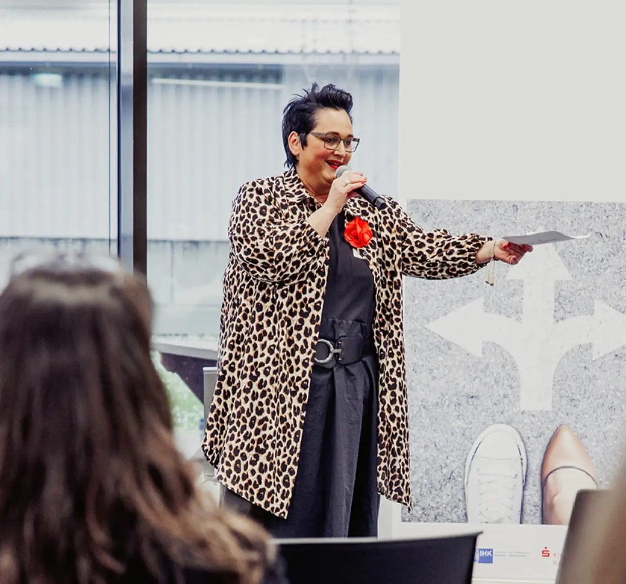 Speakerin Sabine Jung-Bass steht vor Publikum und hält einen Vortrag